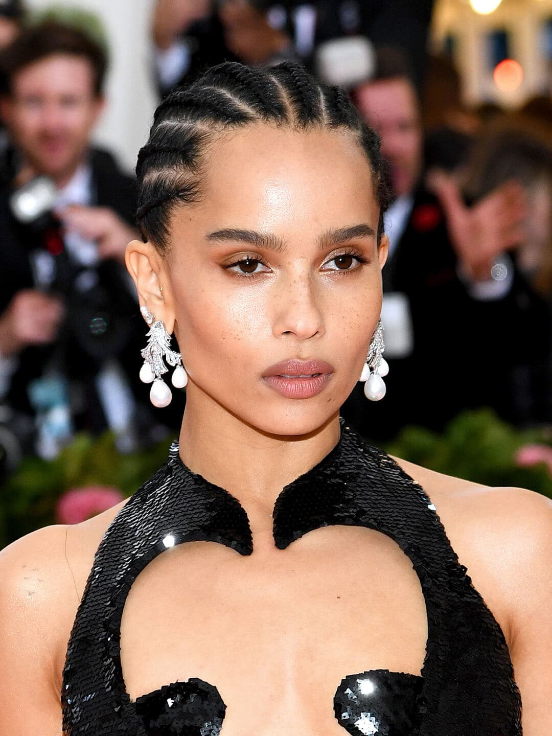 Zoe Kravitz looking glam in a black sequined dress matched with a braided hairstyle and silver and pearl earrings
