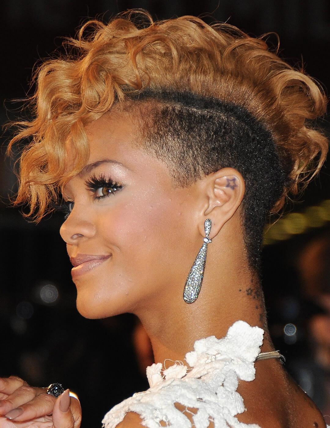 Rihanna sporting a two-toned undercut hairstyle, neutral makeup look, silver dangling earrings, and white floral dress at the red carpet