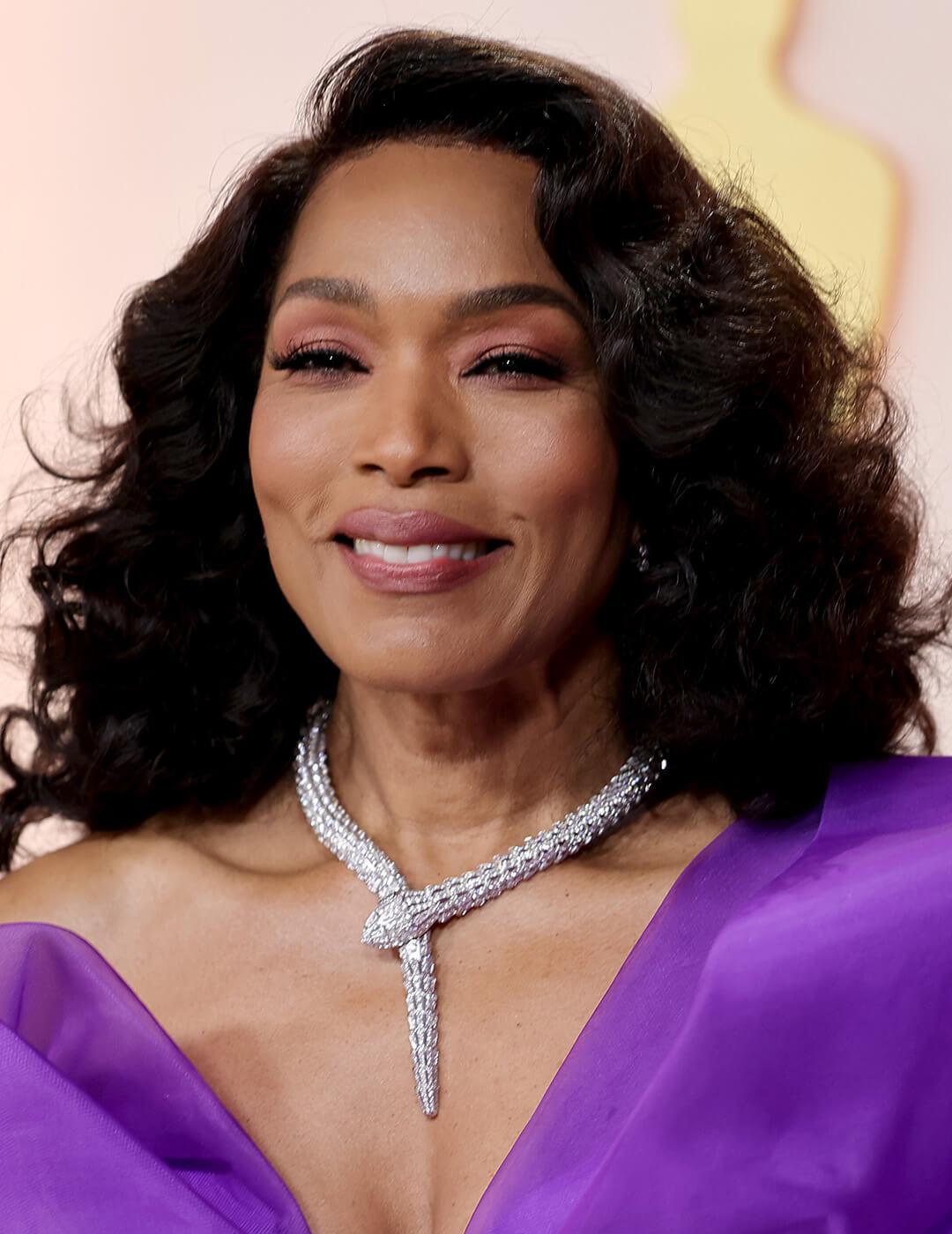 A photo of Angela Bassett with a long layered hairstyle and wearing a purple dress