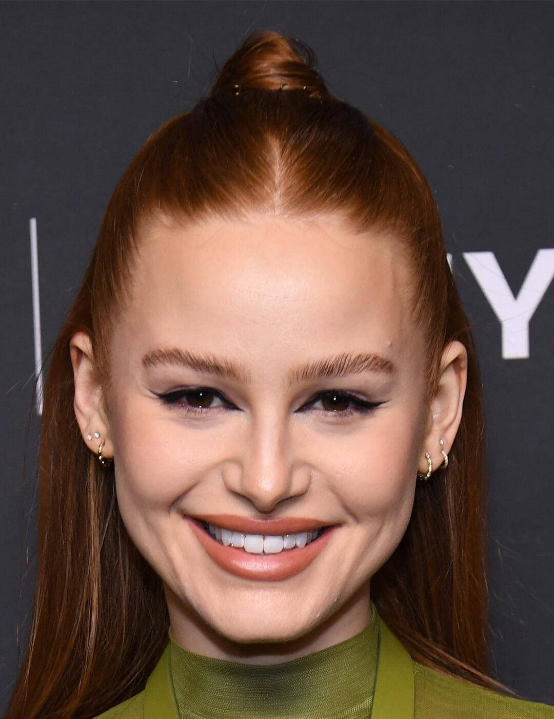 Madelaine Petsch looking glam with a dramatic cat-eye look paired with a slick semi-high bun hairstyle