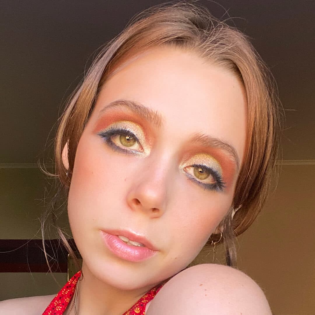Devyn Severson in a room rocking a shimmery gold and matte orange eyeshadow look