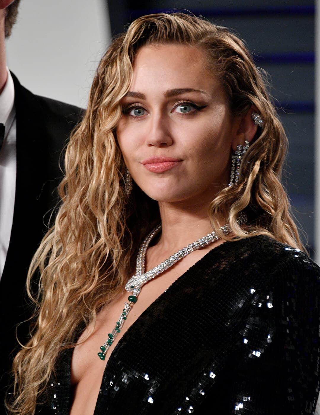 Miley Cyrus looking glam in a wet look curly hairstyle and black sequined dress