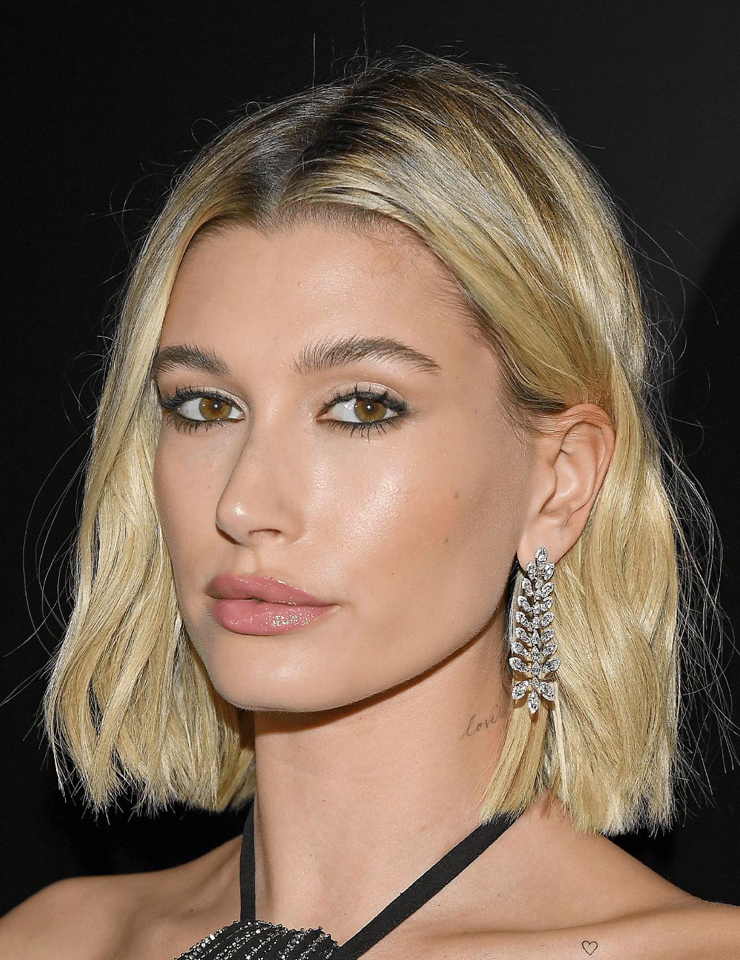 Hailey Bieber rocking a bob hairstyle, neutral makeup look, and dangling diamond earrings
