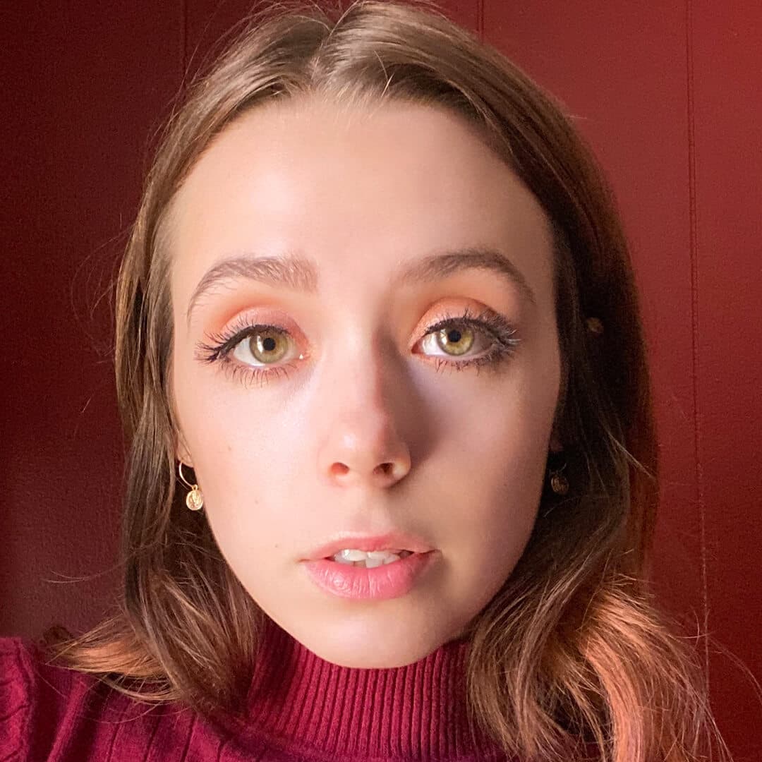 Devyn Severson in a maroon turtle neck rocking a no-makeup makeup look against maroon background