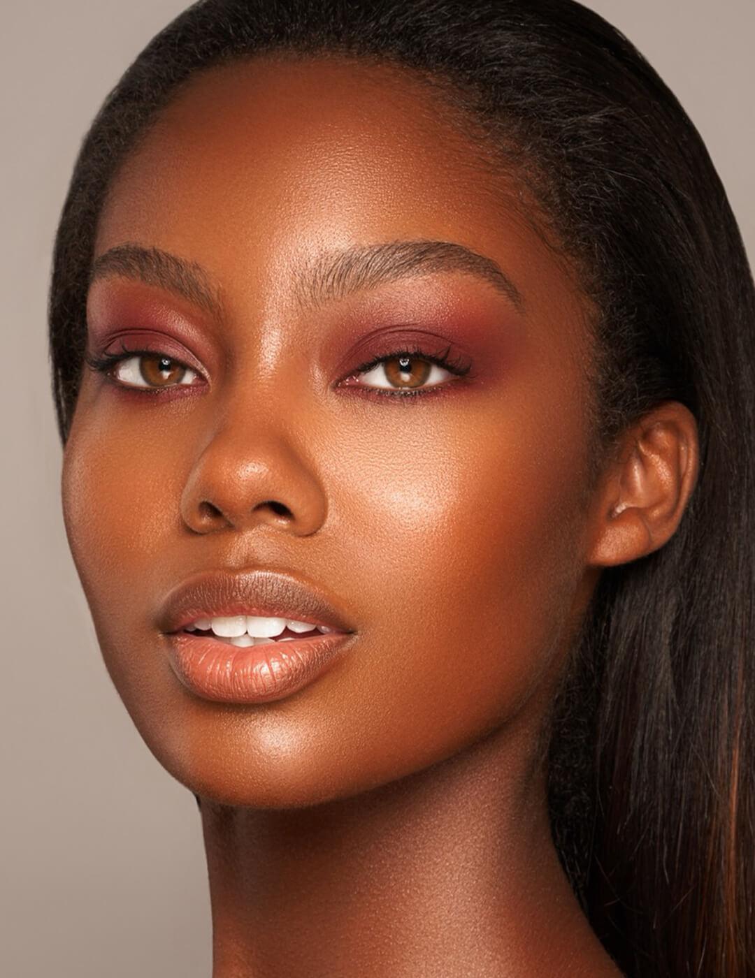 A photo of a Black woman looking beautifully wearing a burgandy metallic eyeshadow and rich blush on