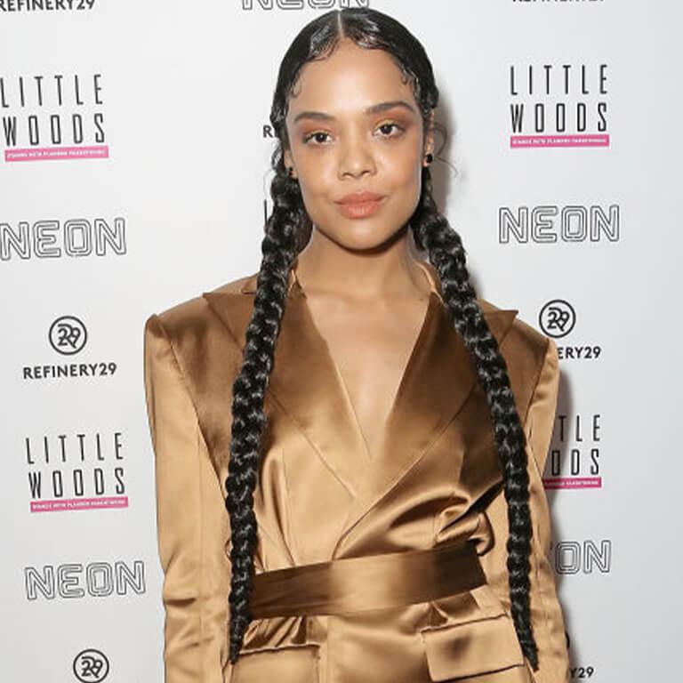 An image of Tessa Thompson showing her very long braided pig tail hairstyle