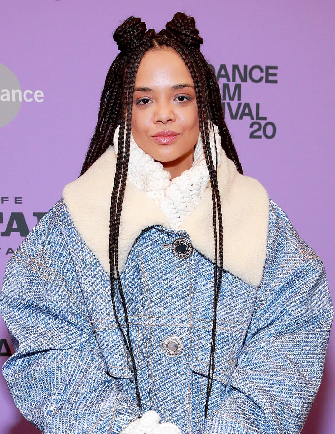 Tessa Thompson looking cool in a big, denim winter jacket and braided hairstyle with space buns