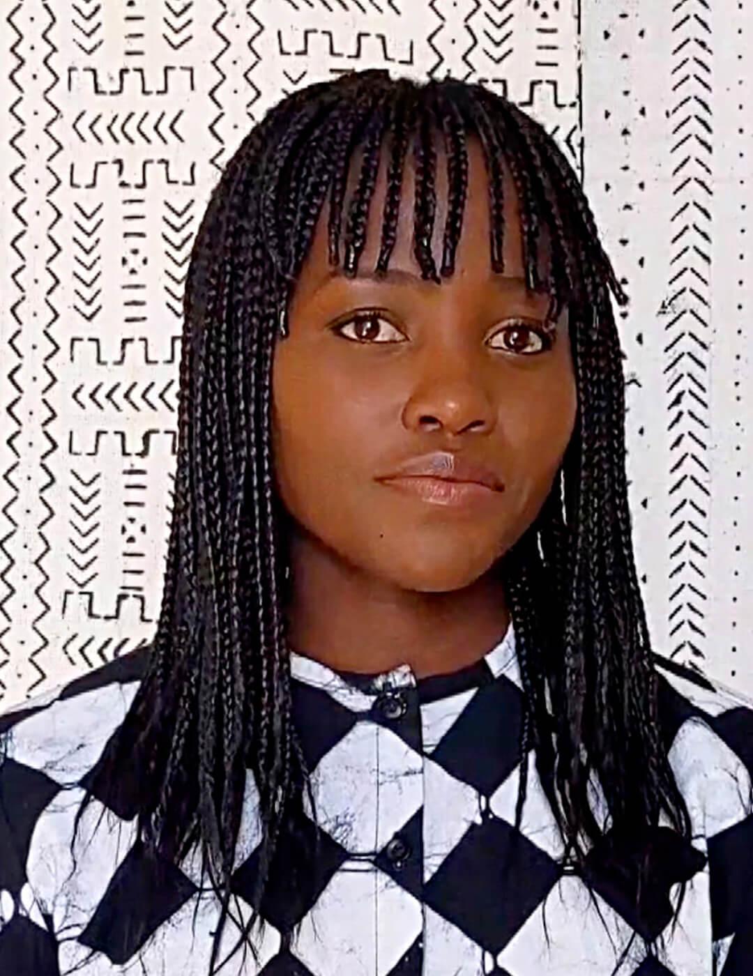 Lupita Nyong'o looking chic in a black and white geometric outfit and braided hairstyle with braided bangs