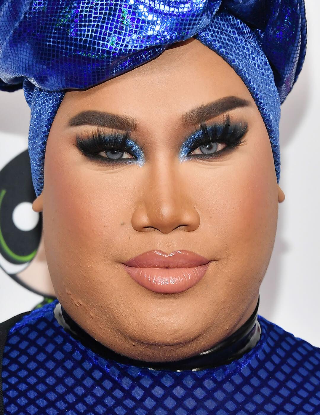 Close-up of Patrick Starrr rocking a sultry cobalt blue eyeshadow makeup look paired with glossy nude lips