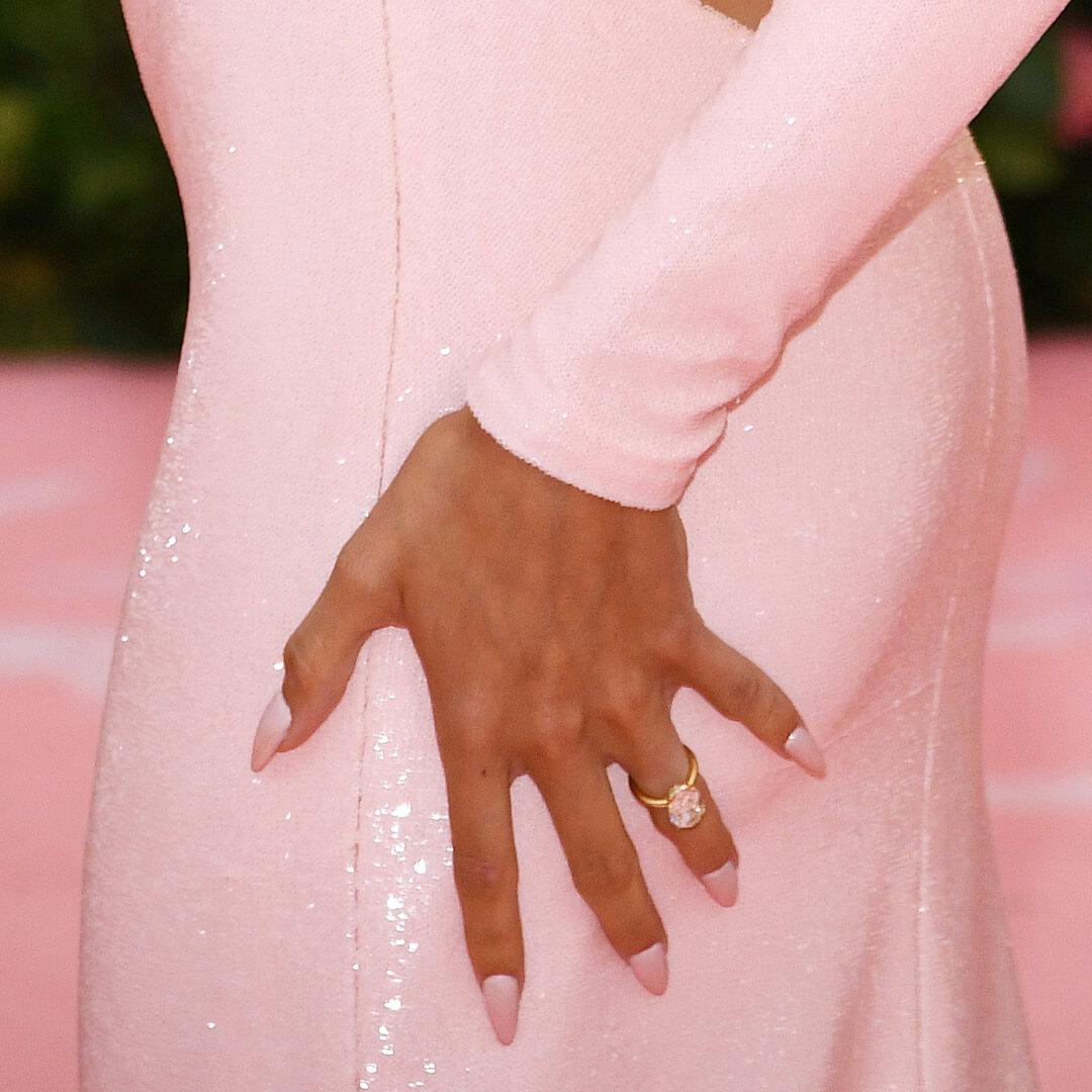 Close-up of Hailey Bieber's hand with matte pink ombre nails resting on her glittery pink dress