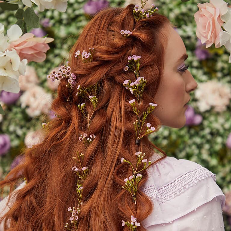 A close-up image of a red-haired model's bubble braids with flower stems