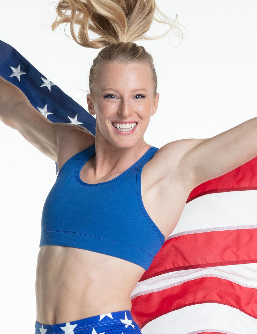 Sandi Morris smiling and holding the US flag behind her back