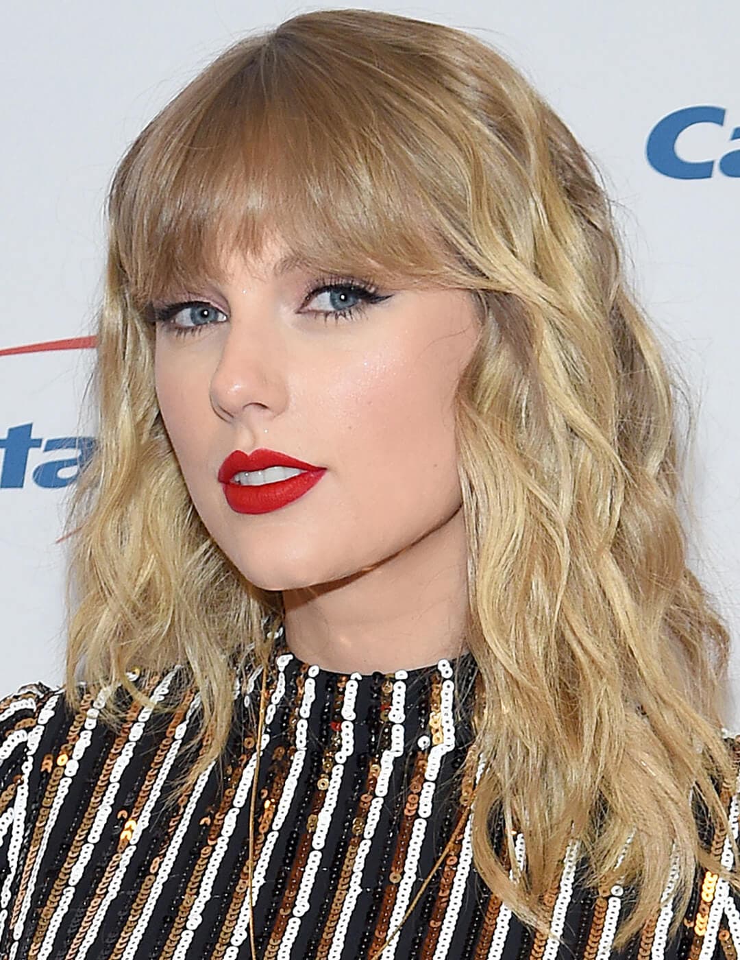 A photo of Taylor Swift with a shag cut hairstyle with bold red lips and wearing a sequin dress