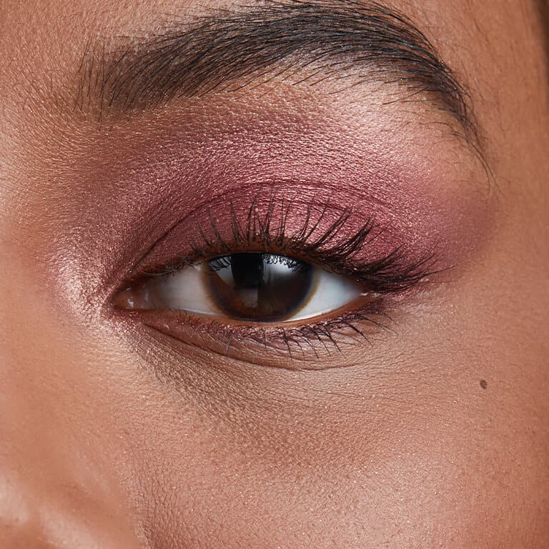 A closeup image of model Martine Fox's eye with dark, metallic berry eyeshadow