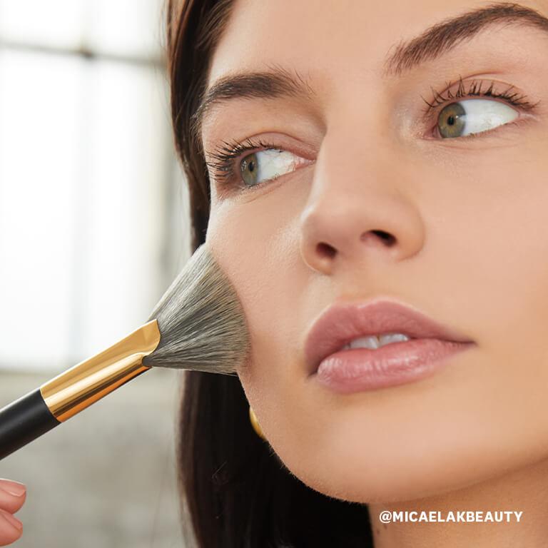 An image of a model using a fan brush in applying contour makeup