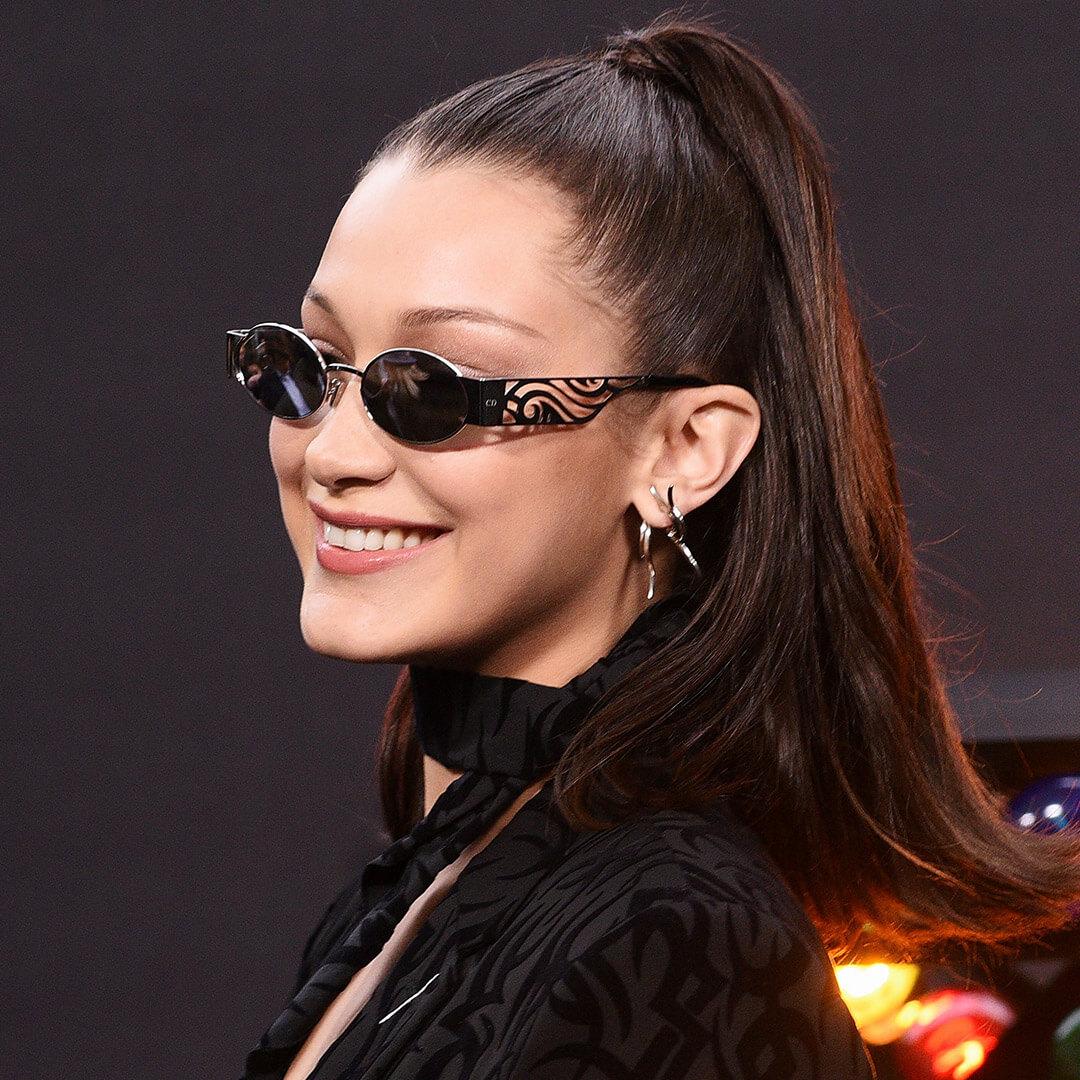 A photo of Bella Hadid with a high ponytail and a pair of sunglasses