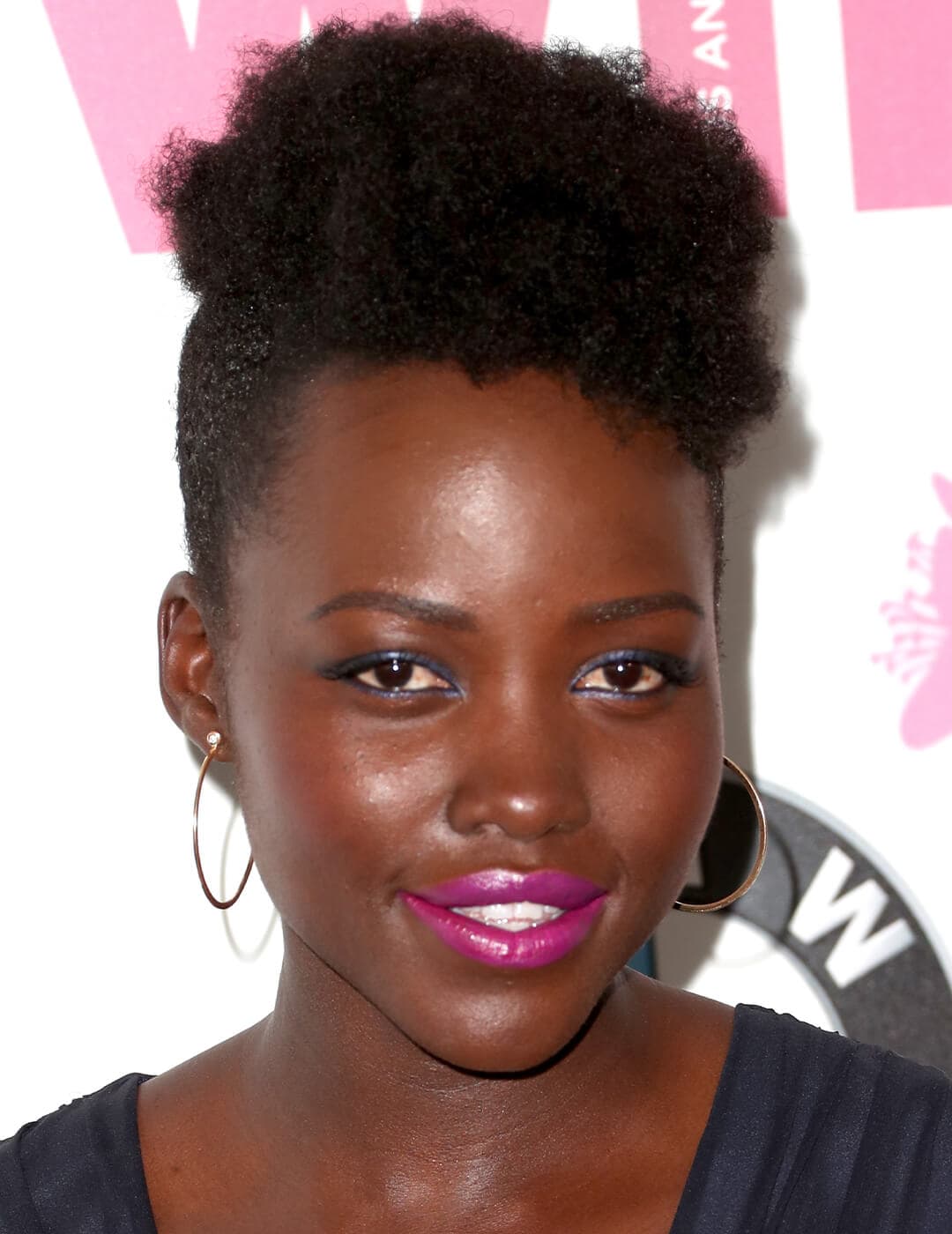 Lupita Nyong'o rocking minimal makeup paired with bold pink lips and her natural curls with undercut hairstyle