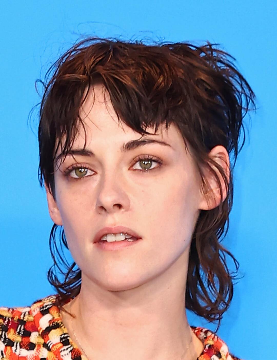 A photo of Kristen Stewart with a modern mullet with a blue background
