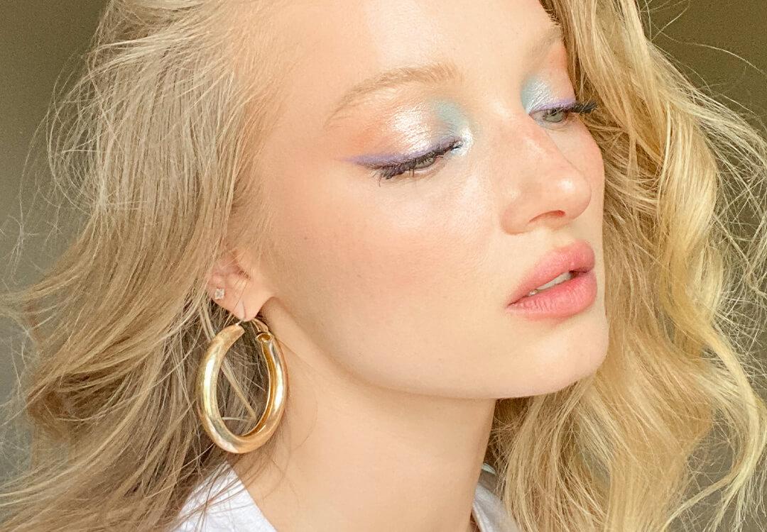 Close-up image of Ash Walker wearing a gold hoop earring and rocking a shimmery pastel eyeshadow look