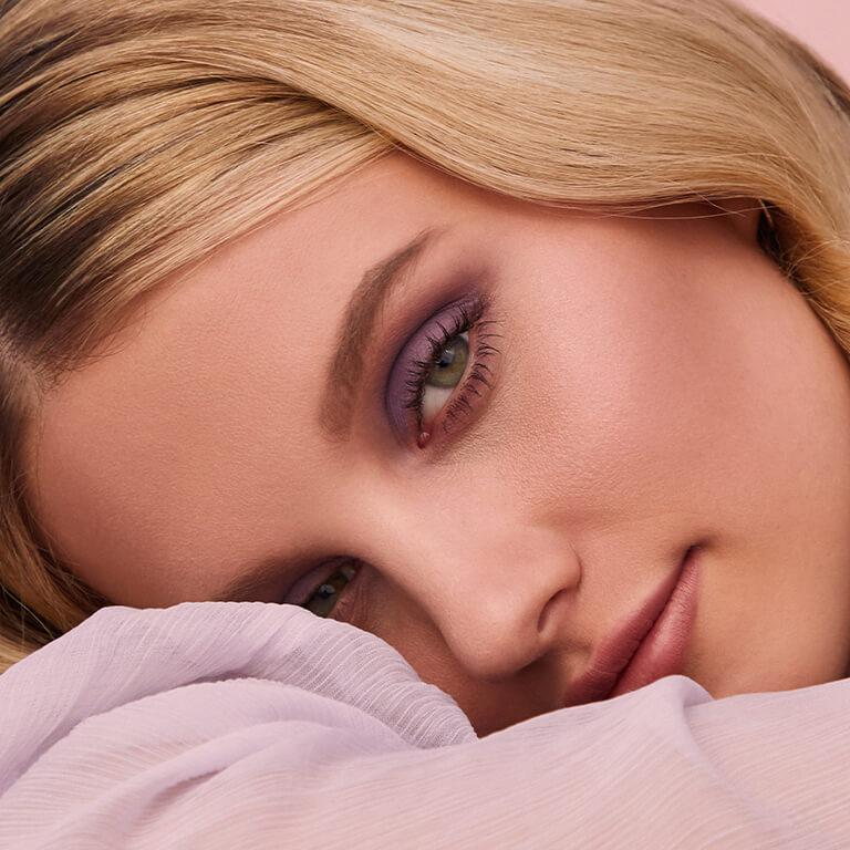 A closeup image of a model rocking a smoky purple eyeshadow look