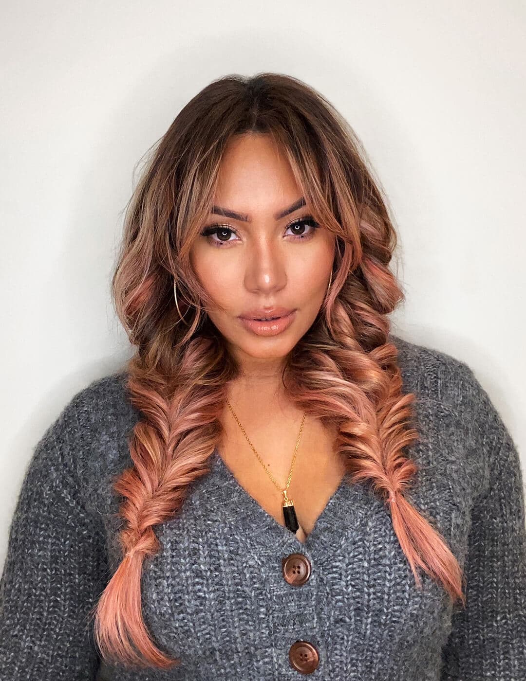 Profile image of Cynthia Alvarez wearing a dark gray cardigan and rocking a rose gold fishtail braided hairstyle
