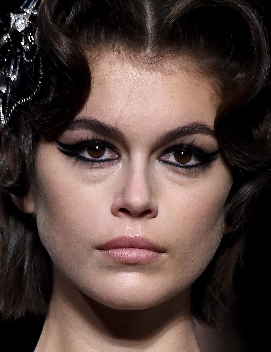 Close-up of Kaia Gerber rocking a exaggerated winged eyeliner look and nude pink lips