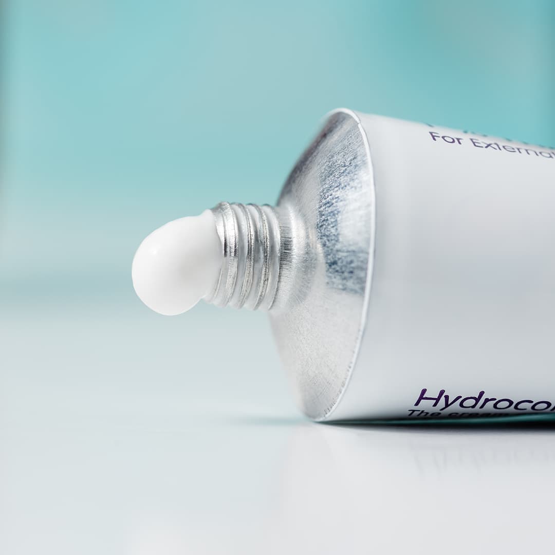 A tube of hydrocortisone cream on a domestic bathroom top with a blue background
