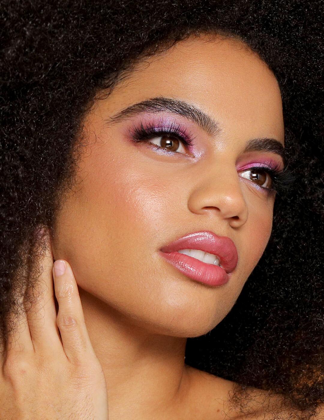 A photo of a woman looking gorgeous on her fuchsia eye look while holding her neck in one hand