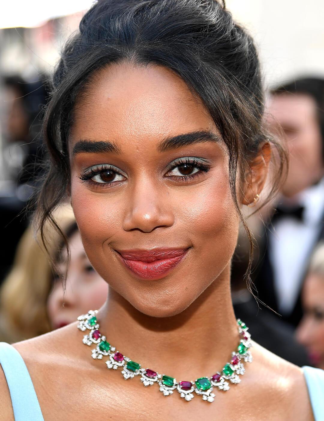 Laura Harrier rocking a baby blue eye makeup look, ruby and emerald necklace and baby blue dress