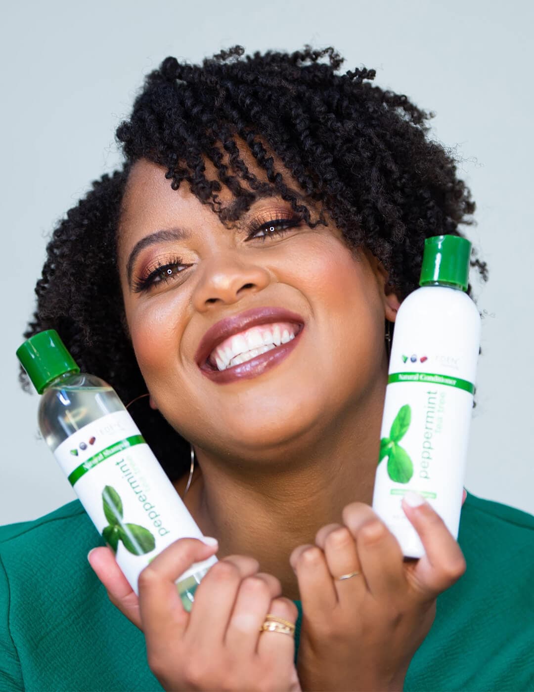 EDEN BODYWORKS founder Jasmine Lawrence posing and holding two bottles of products