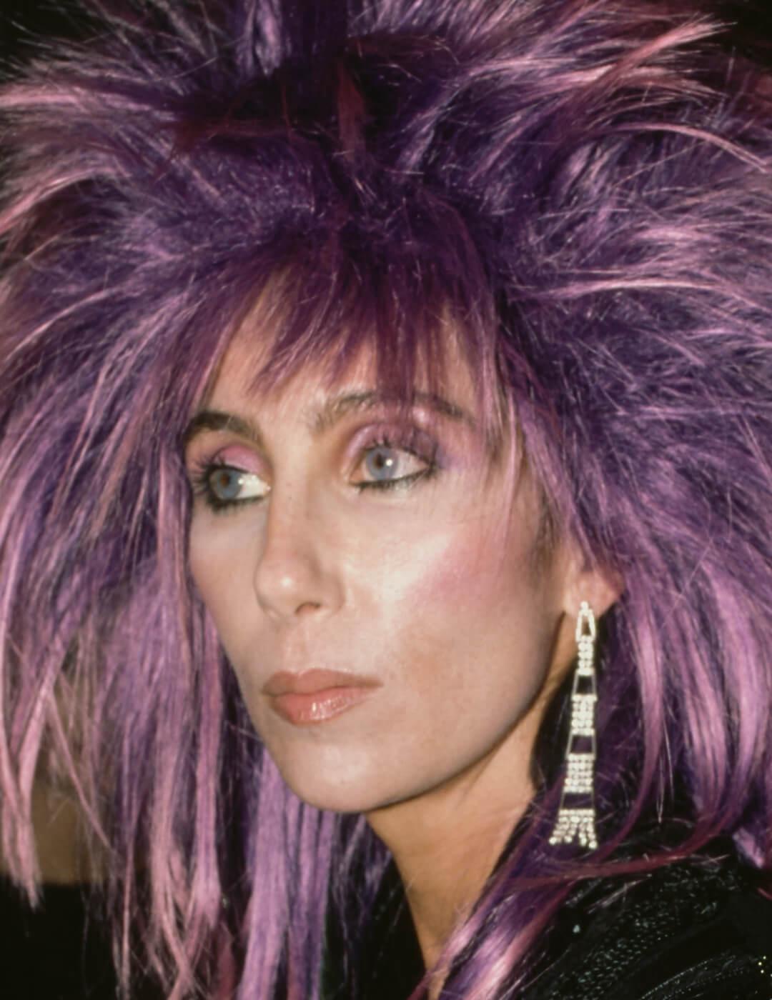 A photo of Cher rocking a bright purple hairstyle with a pink smoky eyes and pink lips