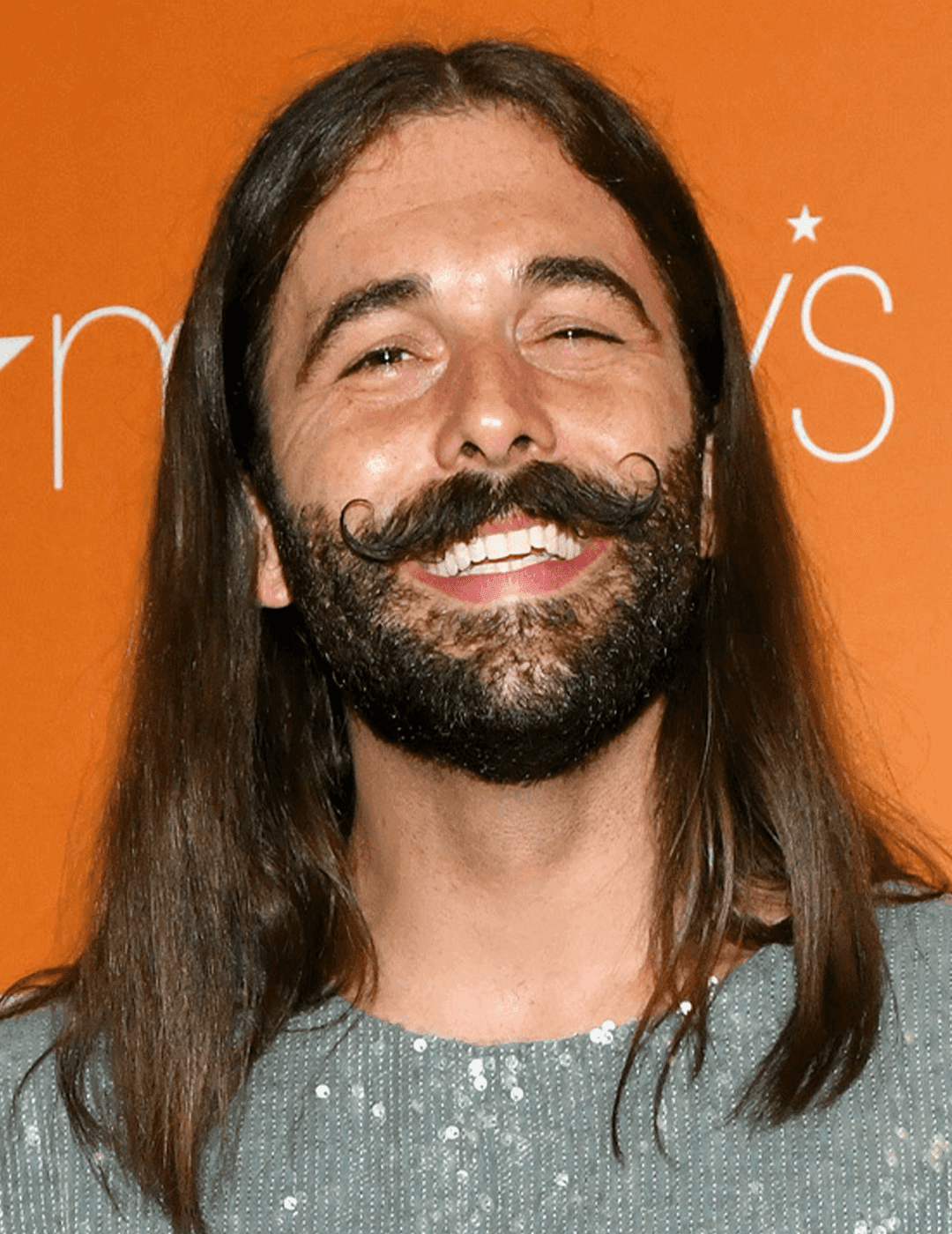 Jonathan Van Ness rocking a sequined top and long hairstyle complete with beard and mustache