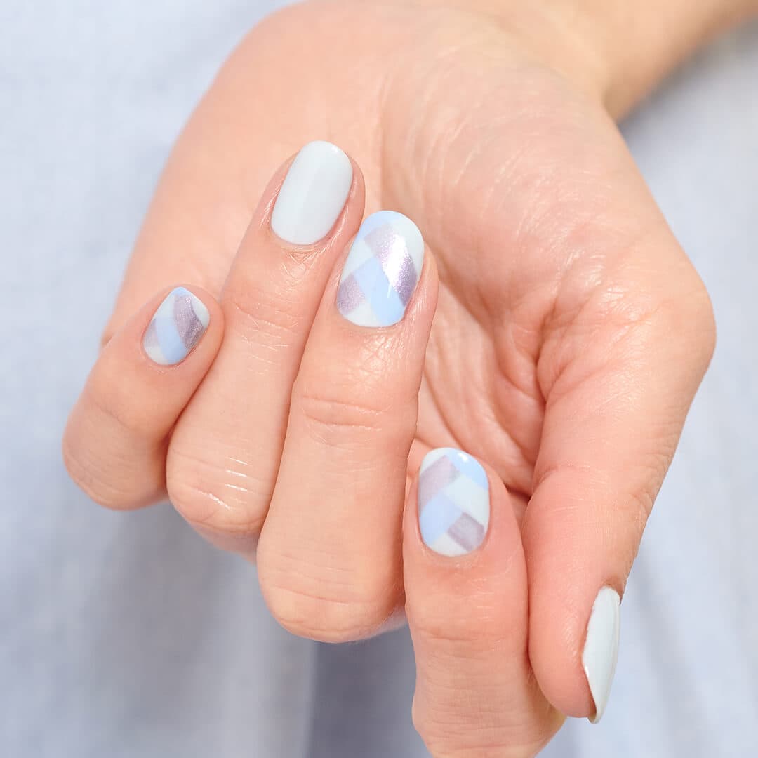 Close-up image of a hand with light blue scales nail art mani