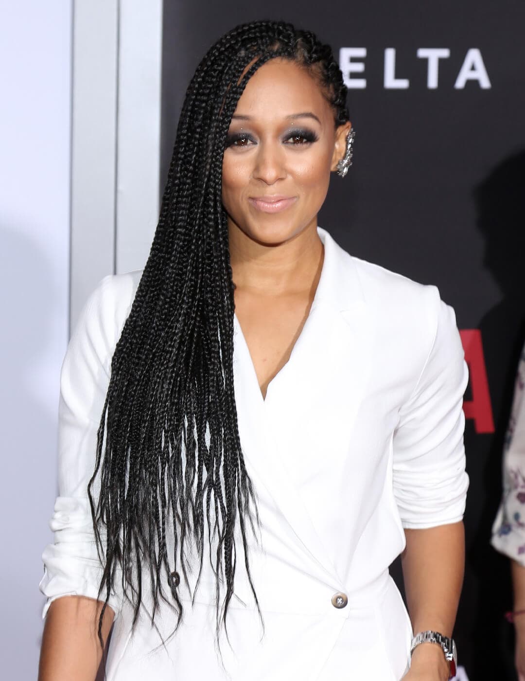 Tia Mowry looking chic in a white ensemble and side-swept braided hairstyle