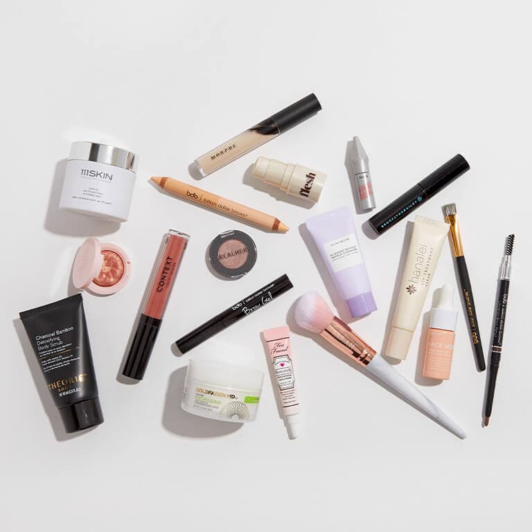 An image of makeup, skincare, and hair care products and beauty tools laid on a white surface