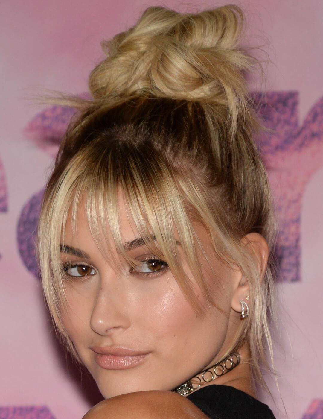 A photo of Hailey Bieber wearing a chic black top elegantly baring her shoulders adorns a necklace that resembles a stylish bangle