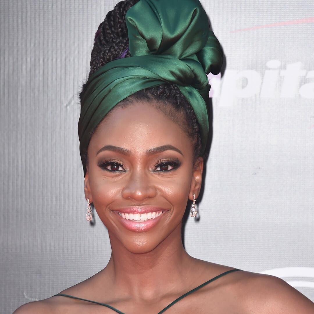 A photo of Teyonah Parris with a high bun and a green silk headband