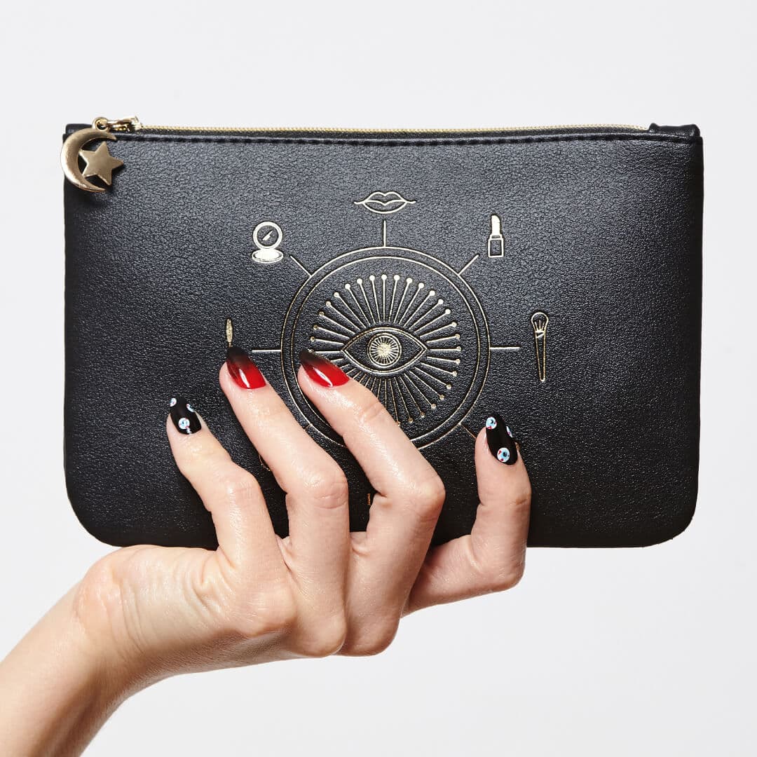 Close-up image of model's hand with black and red graphic nail art mani holding the IPSY October 2020 Glam Bag