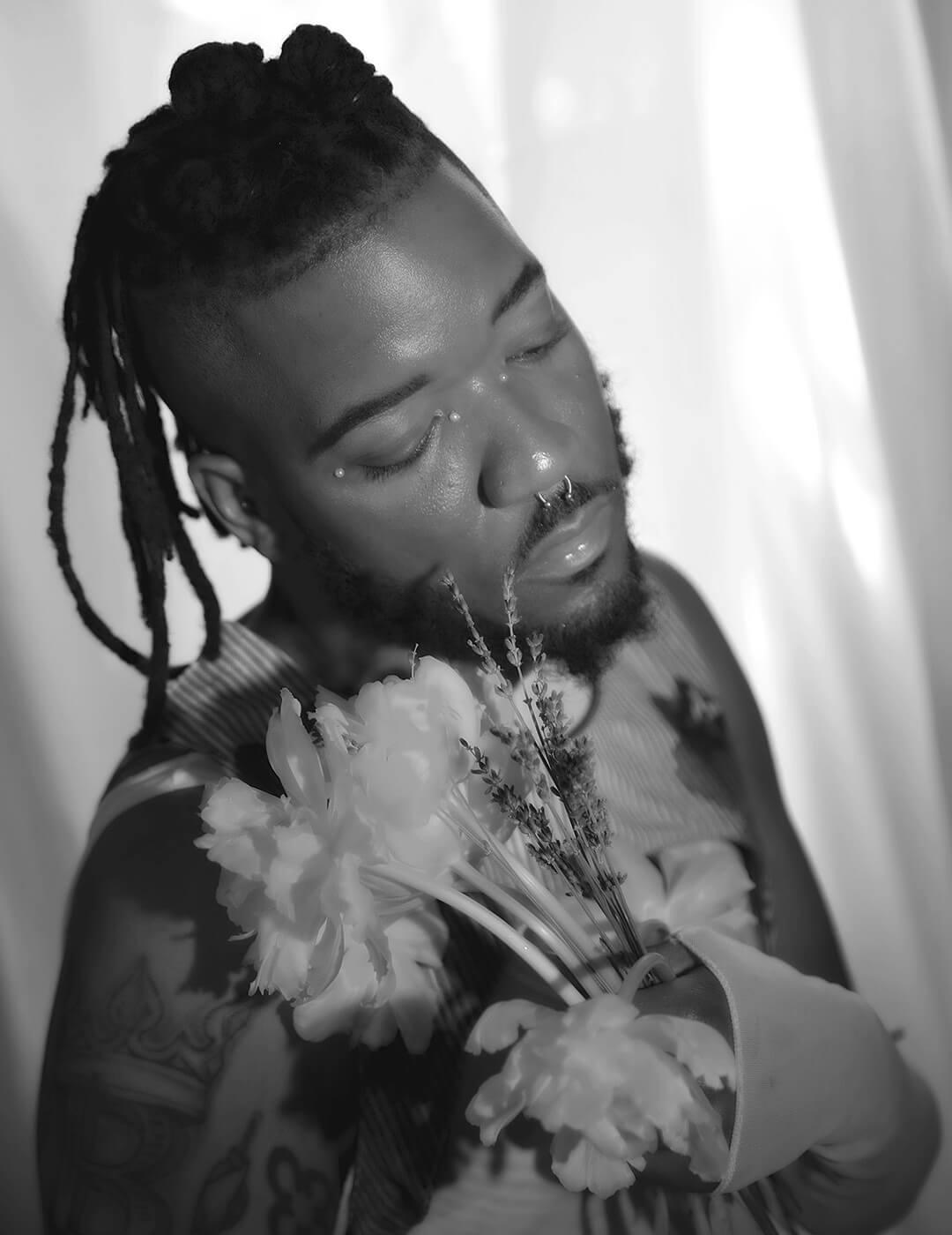 Black and white portrait of Bryce Anthony posing and holding a bouquet of flowers