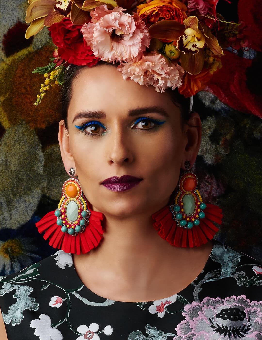 Portrait of Reina Rebelde rocking a floral head piece against floral background
