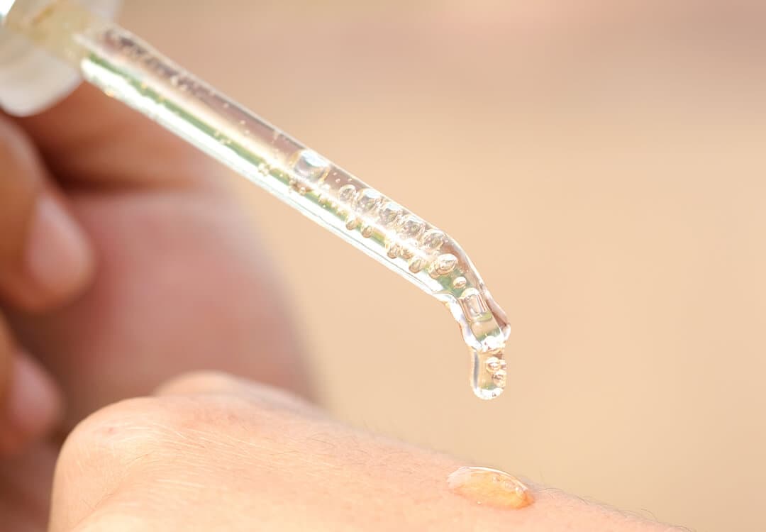An image of a dropper with clear liquid on skin