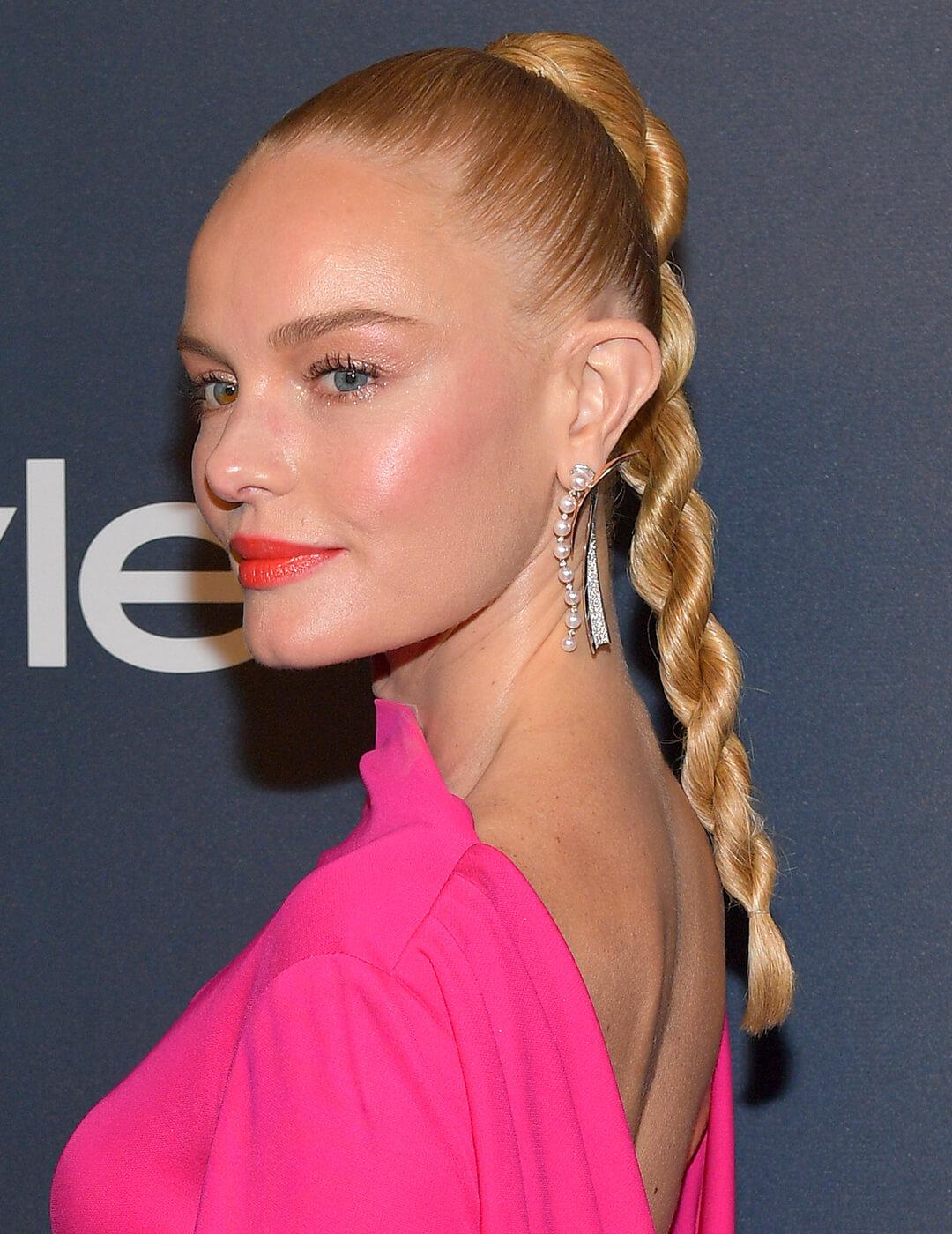 Kate Bosworth rocking a hot pink dress, minimal makeup look, silver dangling earrings, and twisted braids high ponytail hairstyle