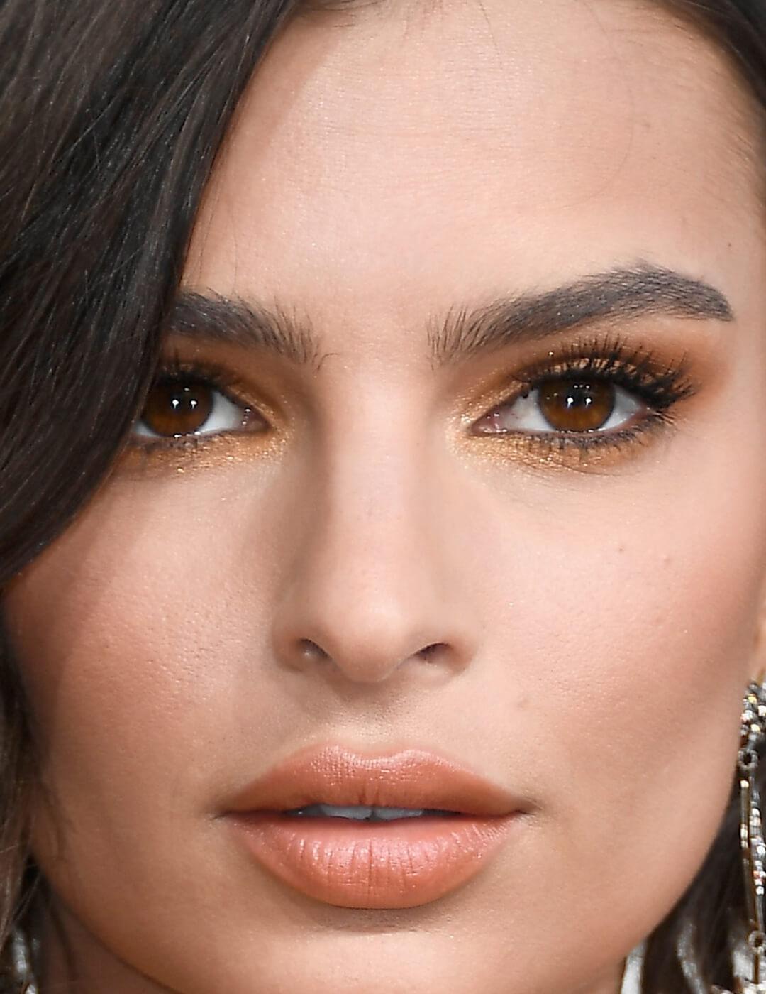 Close-up image of Emily Ratajkowski wearing a sultry gold eyeshadow makeup look