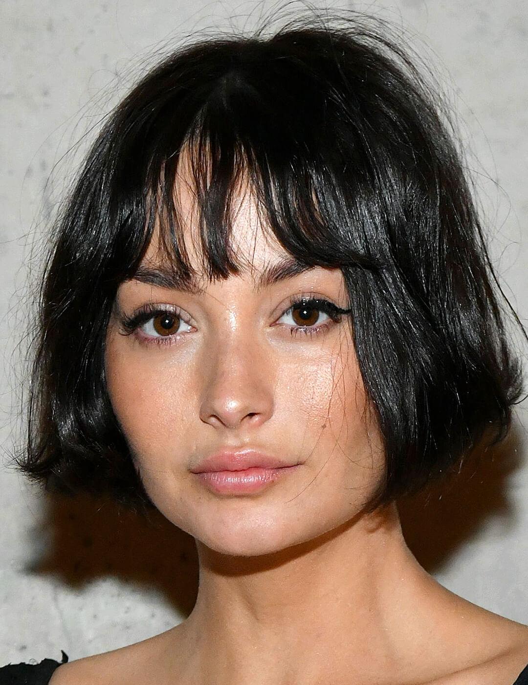 An image of Taylor LaShae wearing a messy French bob haircut on a gray background