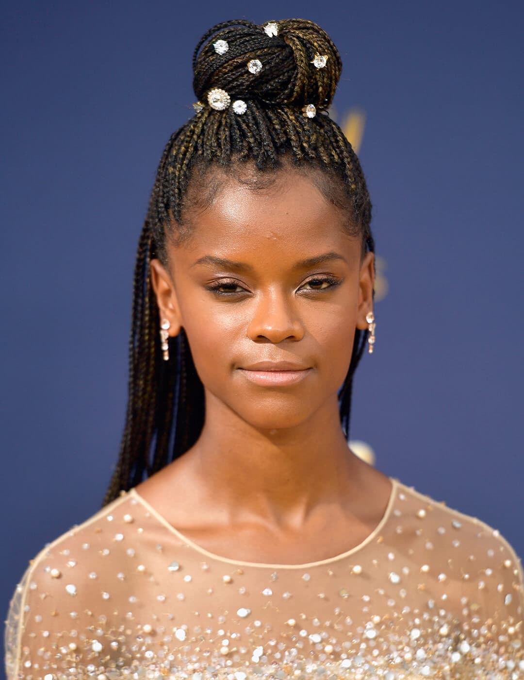 Letitia Wright rocking a braided hairstyle embellished with crystals and sheer nude dress with crystals