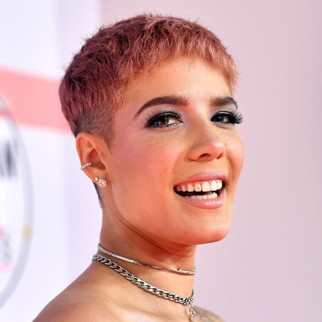 Close-up of a smiling Halsey rocking pink pixie cut hairstyle and pink eyeshadow makeup with bold lashes