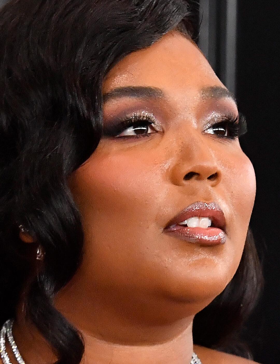 Lizzo rocking a glam smoky eyeshadow makeup look with fluttery false lashes