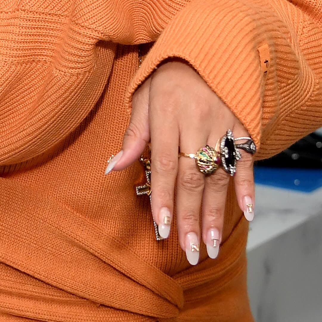 Close-up of Rihanna's nude nails with gold letter decals spelling out FENTY