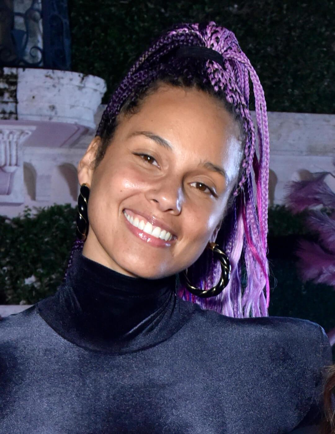 Smiling Alicia Keys rocking a purple braided high ponytail hairstyle