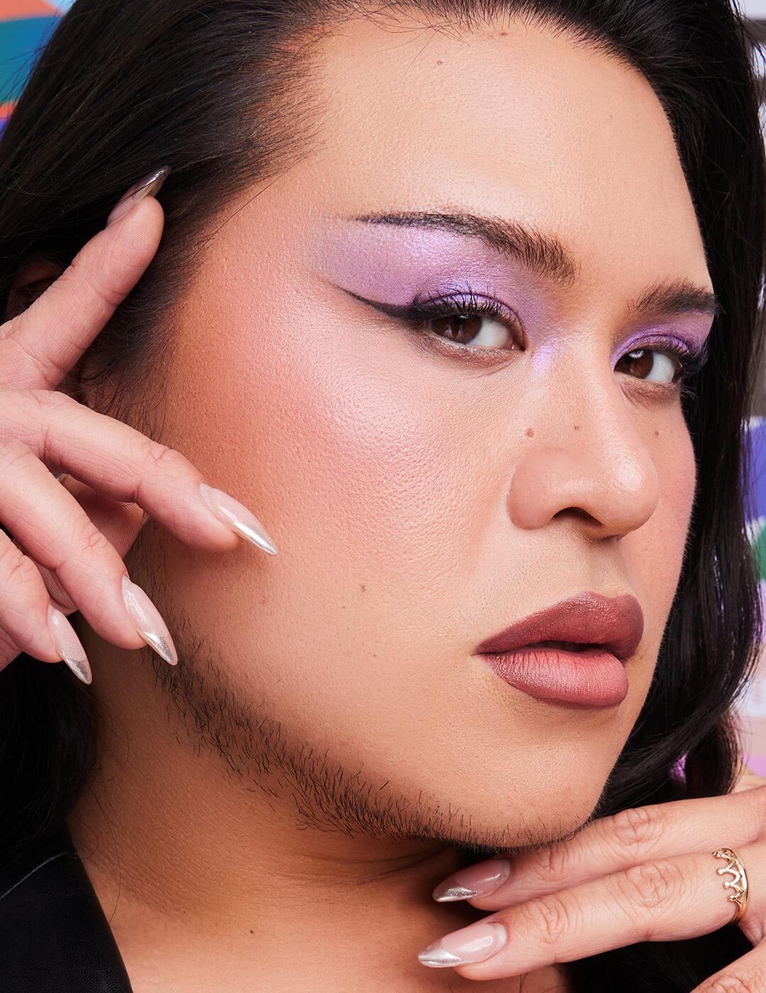 Close-up of Alyx Liu posing and rocking a shimmery purple eyeshadow look with winged eyeliner